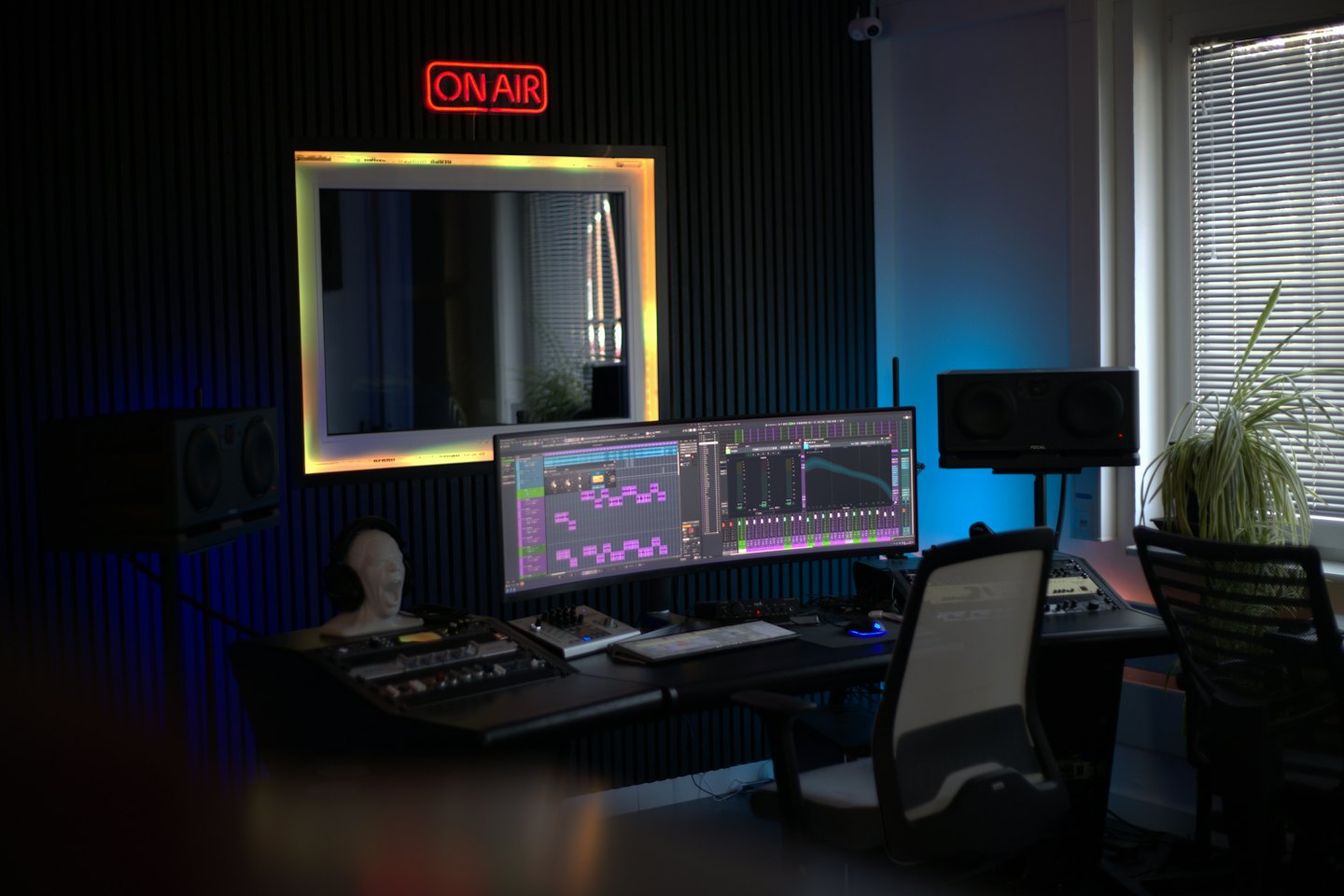 Studio di produzione musicale con monitor ultrawide e console di missaggio.
