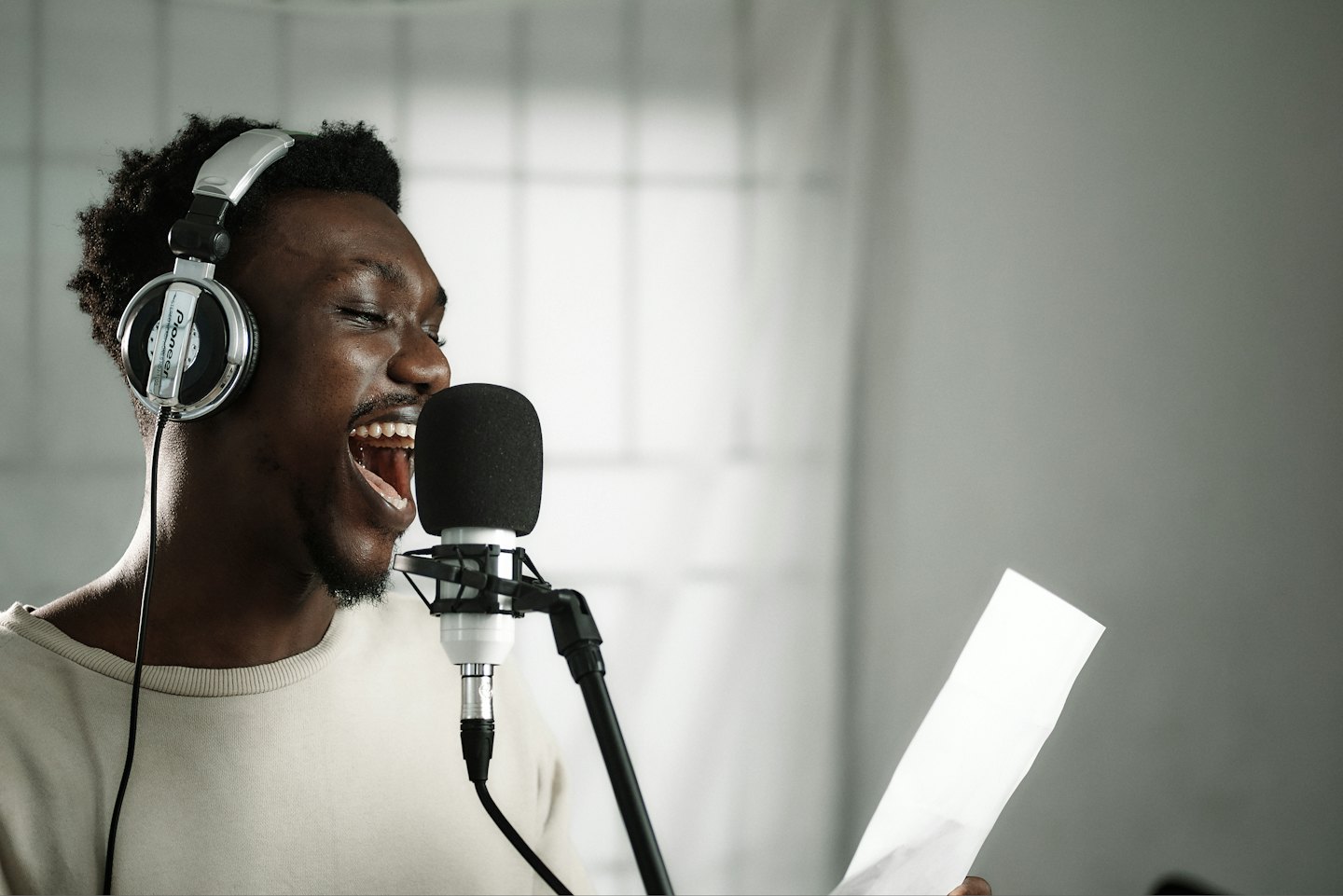 Giovane uomo nero canta al microfono con cuffie.