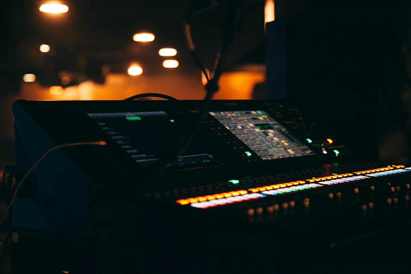 Console di missaggio audio digitale con pulsanti e schermi luminosi.